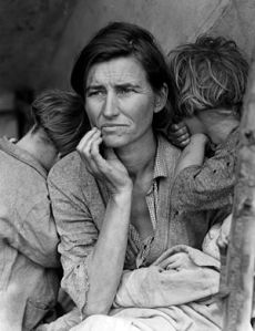 Wary looking woman sits with a baby in her arm and her chin in her hand. Two children stan on ether side of her, brying their faces in her shoulders.