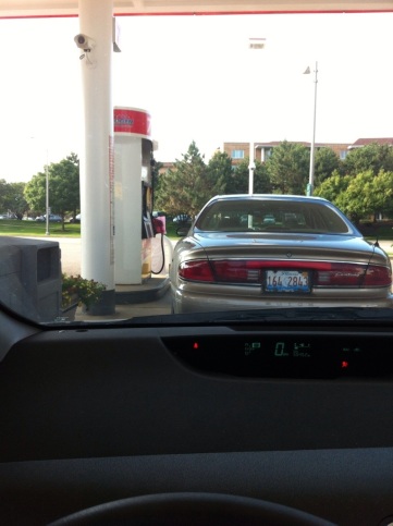 Picture taken from the driver's seat of the car in front of them at a gas pump. The car is off with no one near it. There is a pink "out of order" sign on the handle.